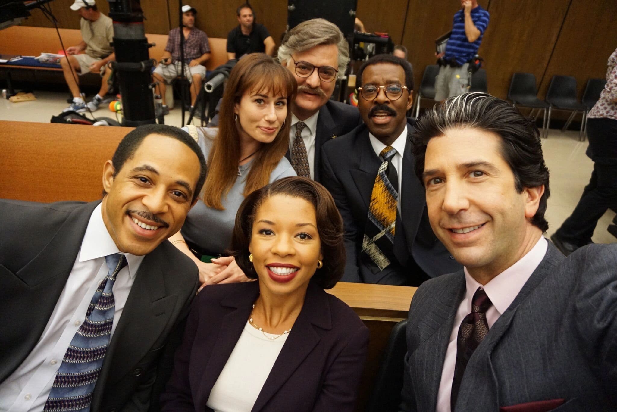 Six actors in period wardrobe on a courtroom set