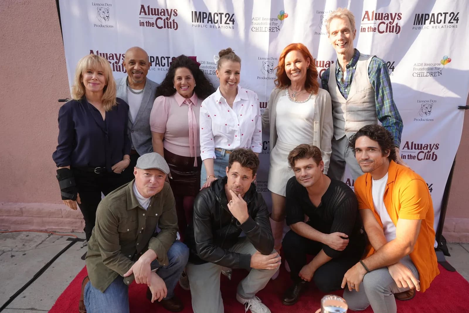 A group on a red carpet in front of an Always In The Club step and repeat