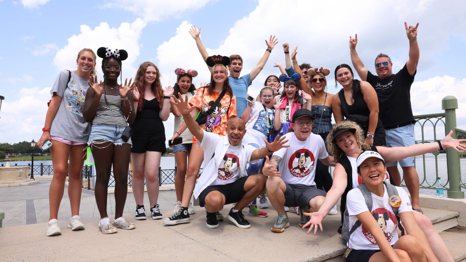 A large group outdoors on a sunny campus, several wearing Mickey ears